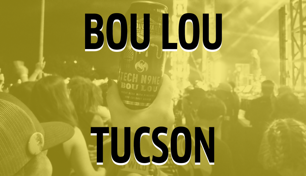 A person holds up a can of Bou Lou beer at an outdoor concert in Tucson. The crowd is visible under yellow lighting, watching a performer on stage.