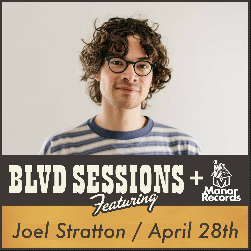 A person with curly hair and glasses, wearing a striped shirt, stands against a plain backdrop. Text on the image reads: "BLVD SESSIONS + Manor Records Featuring Joel Stratton / April 28th.
