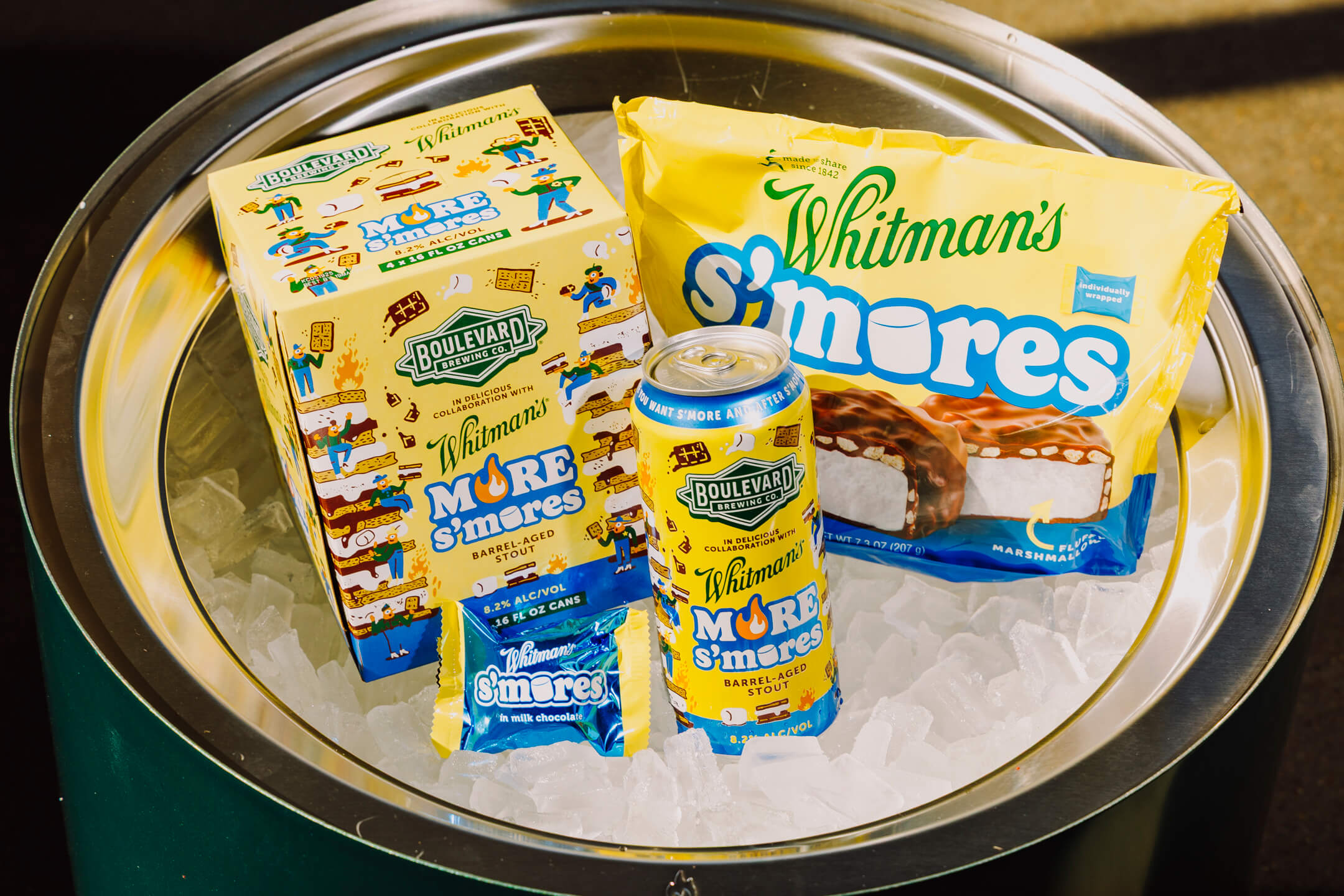 A can of Boulevard Brewing Co. Whitman’s S’mores Beer, a Whitman’s S’mores ice cream bar, a Whitman’s S’mores ice cream sandwich, and their packaging sit on a bed of ice.