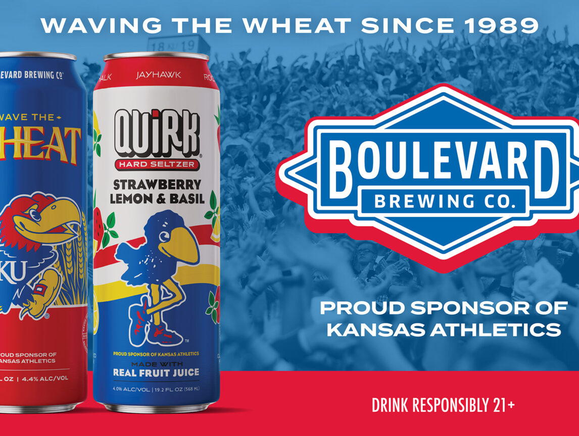 Two colorful Boulevard Brewing Co. cans, featuring Kansas Jayhawks mascots, stand on a red surface with Boulevard Brewing logo and text: “Proud Sponsor of Kansas Athletics” against a backdrop of wheat.