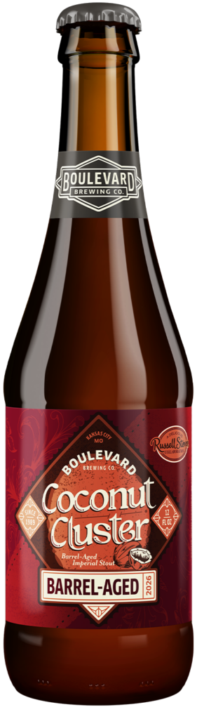 A brown glass bottle of Boulevard Brewing Co. Coconut Cluster Barrel-Aged Stout with a red label, showcasing brewery and beer name, and a small Russell Stover logo.