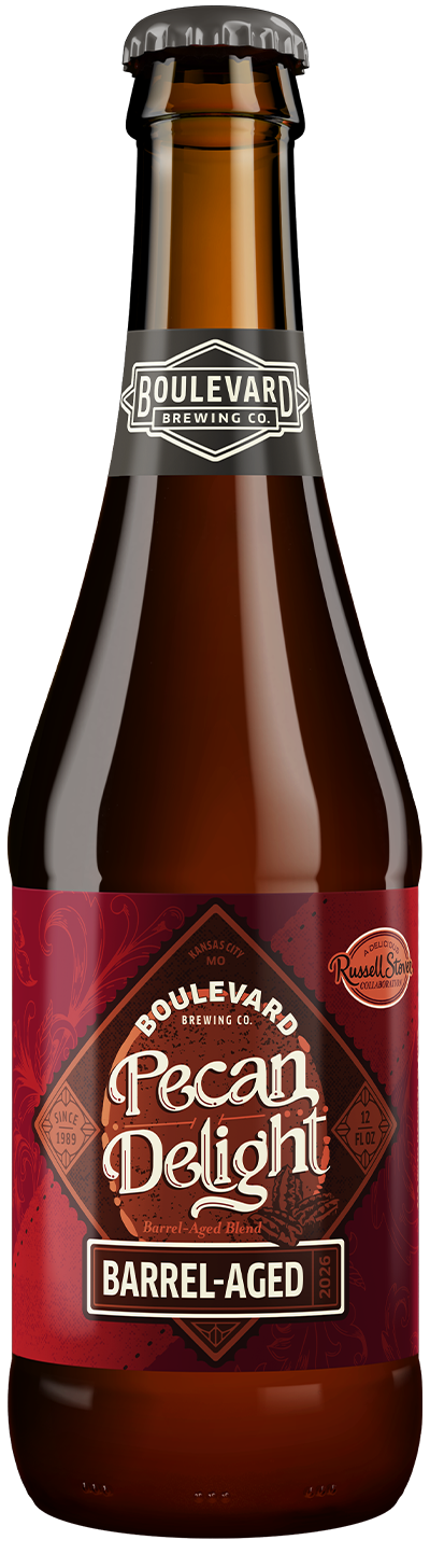 A brown glass bottle of Boulevard Brewing Co. Pecan Delight Barrel-Aged beer, featuring a red label with decorative text and details, and a black cap with the brewery’s logo.